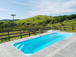 une piscine bleue avec une clôture et une colline dans l'établissement sitio santa Eulalia, à Cunha