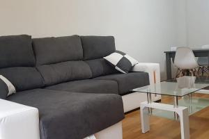 ein Wohnzimmer mit einem grauen Sofa und einem Glastisch in der Unterkunft Maravilloso apartamento en Villagarcia de Arosa in Vilagarcia de Arousa