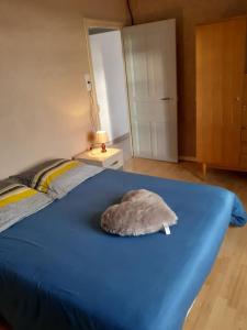 niebieskie łóżko z poduszką na górze w obiekcie Appartement accueillant au cœur de La Margeride w mieście Grandrieu