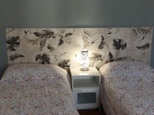 una camera con 2 letti e un comodino con lampada di Le Comari a Milano