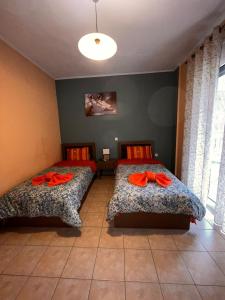 una camera con due letti con fiocchi rossi sopra di Teo's House 2 a Kalabaka