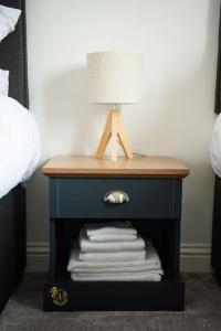 a bedside table with a lamp and towels on it at Chi-Amici-3bed home-St Neots-Near to train station in Saint Neots