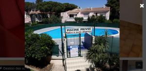 une clôture en face d'une piscine avec une maison dans l'établissement Eureka emeraude, au Cap d'Agde
