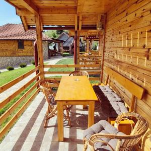une terrasse couverte en bois avec une table et des chaises en bois dans l'établissement Drveni raj Uvac, à Sjenica