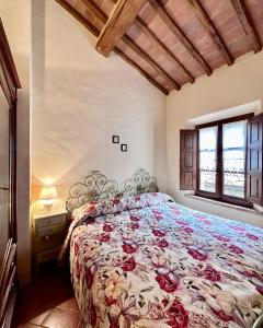 a bedroom with a bed with a floral bedspread at La Casina in Buonconvento