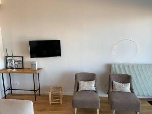 sala de estar con 2 sillas, mesa y TV en Le Touquet : Appt 4 pers face mer en Le Touquet-Paris-Plage