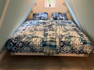 a bed with a blue and white comforter and pillows at Little house in Amsterdam in Amsterdam