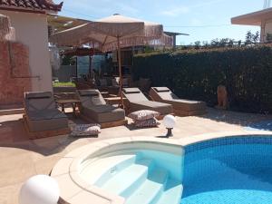 basen na dziedzińcu z krzesłami i parasolem w obiekcie Luxury Villas Chrysa Private Pool & Spa w Nauplionie