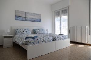 a white bedroom with a large bed with blue sheets at Casa Margherita Bellagio in Bellagio