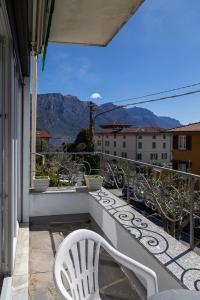 a balcony with white chairs and a view of mountains at Casa Margherita Bellagio in Bellagio