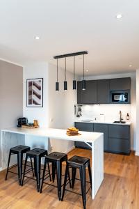 a kitchen with a large white table and four stools at NUVA Apartments in Cologne