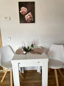 ein weißer Tisch mit zwei Stühlen und zwei Getränken darauf in der Unterkunft Das Ferienhaus mit Aussicht in Pirna