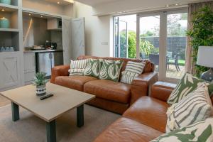 a living room with a brown leather couch and a table at George Hotel, BW Signature Collection in Norwich