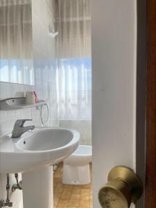 Baño blanco con lavabo y aseo en Hostal El Botero, en Monreal del Campo