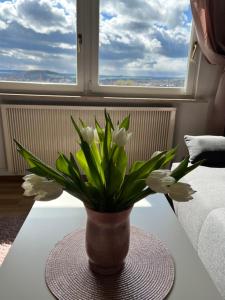 a vase with white flowers on a table in front of a window at Das Ferienhaus mit Aussicht in Pirna