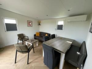 Chalet 't Kwedammertje في Kwadendamme: غرفة معيشة مع أريكة وطاولة وكراسي