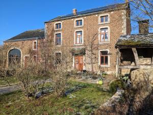 un vieux bâtiment en briques avec une cour devant lui dans l'établissement La Jardinière, à Érezée