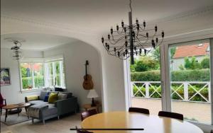 een woonkamer met een kroonluchter en een tafel bij Danish villa with a lovely garden & close to Copenhagen in Gentofte