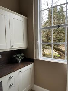 eine Küche mit weißen Schränken und einem Fenster in der Unterkunft The Mulberry Apartment at Langford Hall in Newark upon Trent