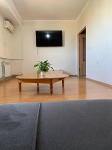 a living room with a table and a flat screen tv at КВАРТИРА с видом на площадь in Shymkent