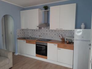 een keuken met witte kasten en een fornuis bij Appartamento a due passi dal mare in Nisporto
