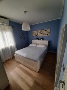 een slaapkamer met een bed met een blauwe muur bij Appartamento a due passi dal mare in Nisporto