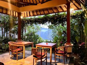 um pátio com mesas e cadeiras sob uma pérgola em The Papas Villas em Tegalalang