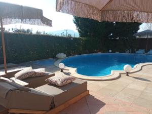 a swimming pool with a couch and an umbrella at Luxury Villas Chrysa Private Pool & Spa in Nafplio