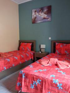 una camera con due letti con lenzuola rosse e una foto a parete di Teo's House 2 a Kalabaka