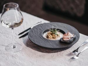 Sonnhof Alpendorf - an adults only place في سانكت يوهان ايم بونغ: طبق من الطعام على طاولة مع كوب من النبيذ