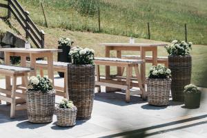 een groep picknicktafels en banken met potplanten bij Sonnhof Alpendorf - an adults only place in Sankt Johann im Pongau