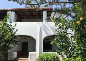una casa blanca con un arco y árboles en Villa Lavinia, en Santa Marina Salina