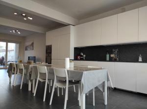 a kitchen with white cabinets and a table and chairs at De Zandparel in De Panne