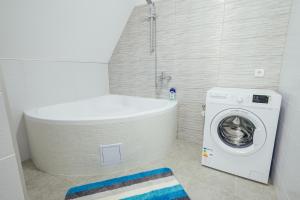 a bathroom with a tub and a washing machine at SkarabeuS in Odorheiu Secuiesc