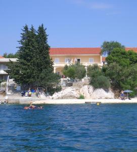 a person swimming in the water in front of a beach at Apartments Tudić in Brodarica