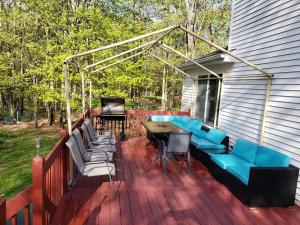 um deque com um sofá azul, uma mesa e cadeiras em Fantastic Poconos home w/ Fireplace + More!!! em Long Pond