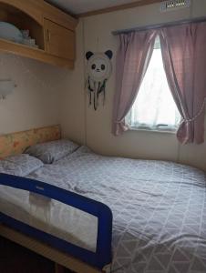 a bedroom with a bed and a window at The Topaz Caravan HF12 in Ingoldmells