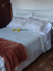 a white bed with a yellow flower on it at Habitación doble in Ciudad Lujan de Cuyo