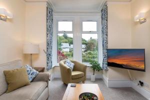 a living room with a couch and a large window at Trewen Cottage in Conwy