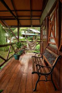 a wooden porch with a hammock and a bench at Sukia Hostel in Drake
