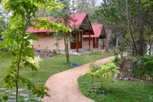 einen Weg zu einem Haus mit rotem Dach in der Unterkunft Ranathisara Grand Cabanas in Kurunegala