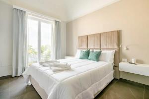 a white bedroom with a large bed with a window at Shoruq in Marsala