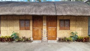 a building with a thatch roof and wooden doors at EDVIL BEACH RESORT 