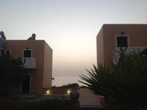 a view of two buildings with the sunset in the background at Archipelagos Apartments in Arkasa