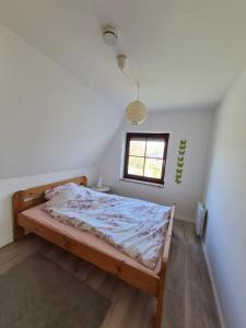 ein Schlafzimmer mit einem Bett in einem Zimmer mit Fenster in der Unterkunft Ferienhaus Kleine Robbe in Friedrichskoog