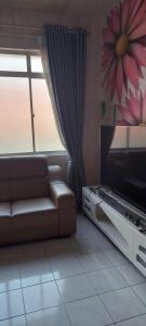 a living room with a couch and a television at Homestay nipah in Bayan Lepas