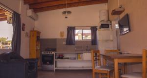 a kitchen with a table and a refrigerator and a table and chairs at Cabañas Buen Ayre in Villa Rumipal