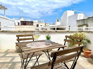 莫諾波利的住宿－Dimore Aria di Mare - Puglia Mia Apartments，一张木桌,配有一杯葡萄酒和两把椅子