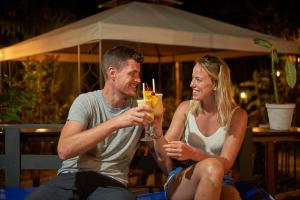 un hombre y una mujer sentados juntos tomando bebidas en Sukia Hostel en Drake
