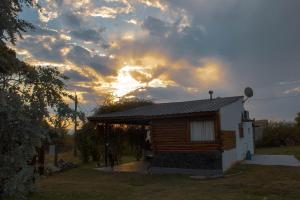 eine Hütte mit Sonnenuntergang im Hintergrund in der Unterkunft Cabañas Buen Ayre in Villa Rumipal